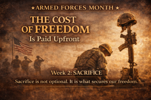 A sepia-toned Armed Forces Month graphic showing a kneeling soldier beside a battlefield cross and rifle beneath the title “The Cost of Freedom Is Paid Upfront,” symbolizing military sacrifice and remembrance.